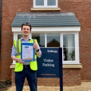 Image shows man holding a STARS accreditation in-front of a new home