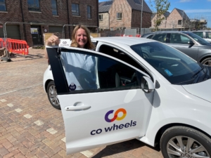 Image shows Claire Fleming smiling stood by a white car branded Co Wheels