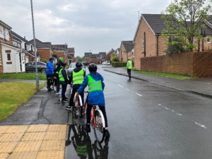 students riding bikes wearing helmets and vis vests on a residential street