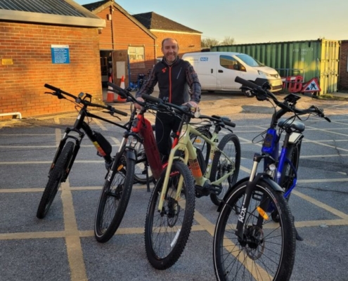 Man stands with four bikes in a row.