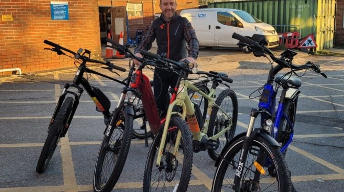 Man stands with four bikes in a row.