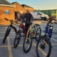 Man stands with four bikes in a row.